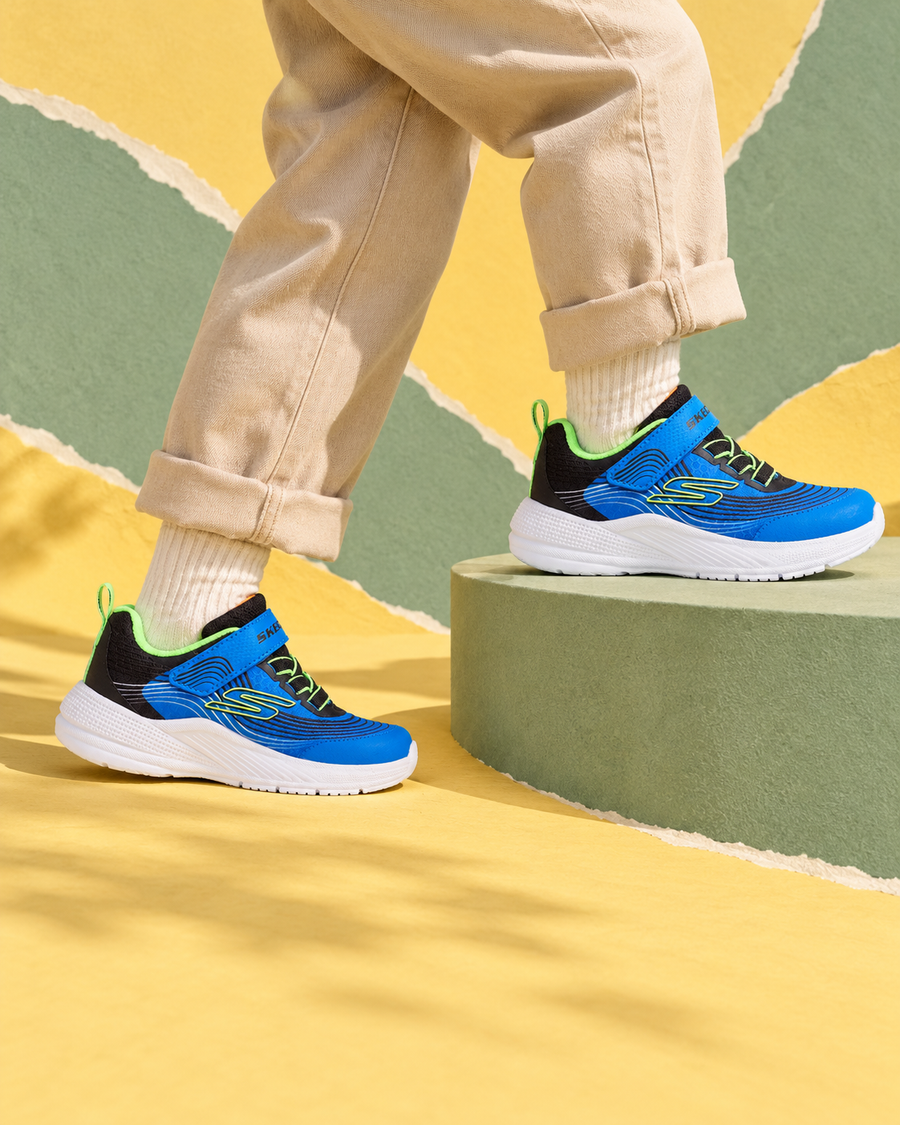 Blue Skechers children’s trainers stepping onto a sage-green platform